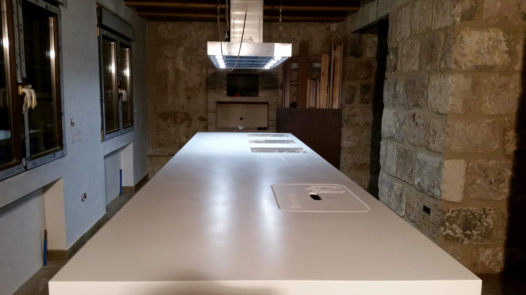 Cocina rústico-moderna con piedra y encimera blanca